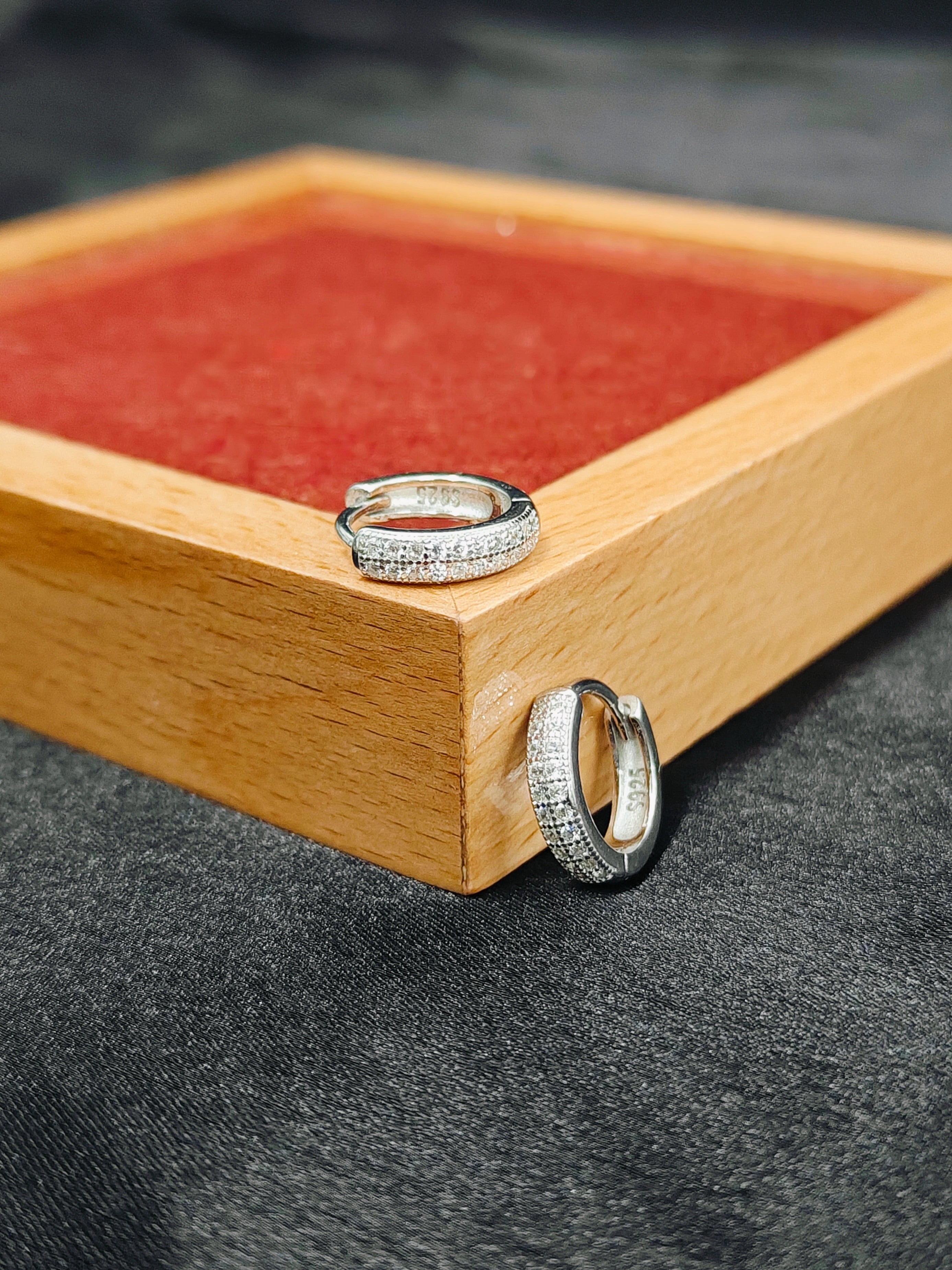 Two silver rings on a wooden tray with a red interior.